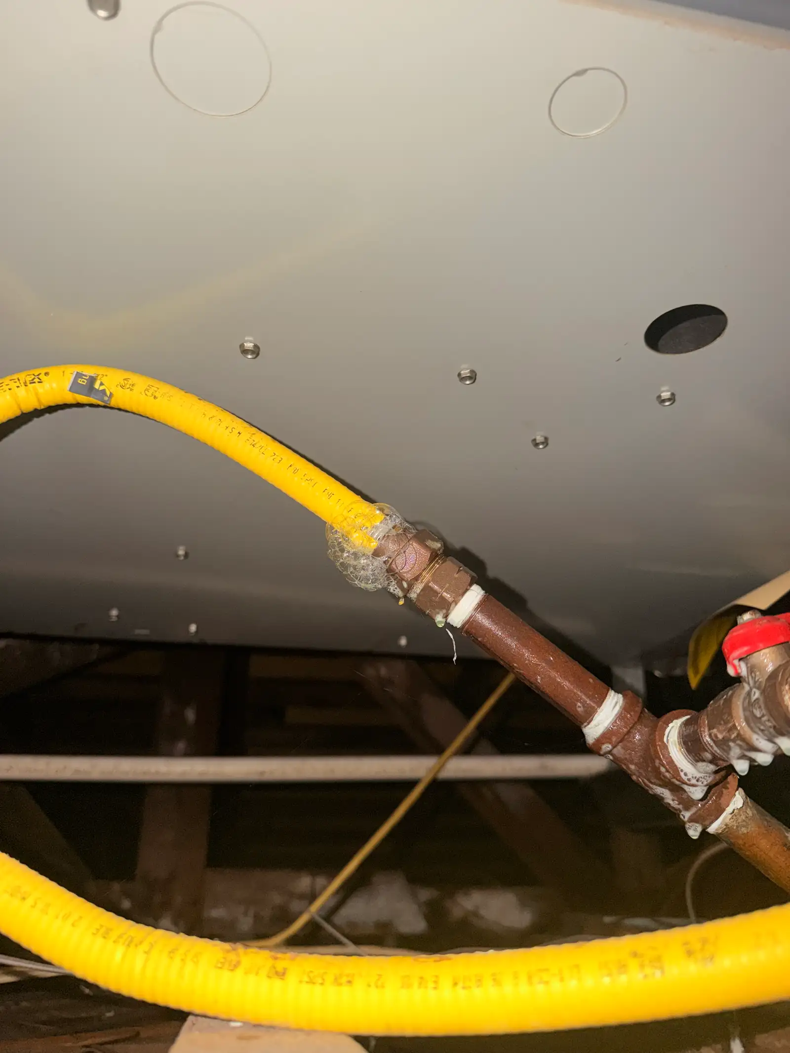 Soap-bubble gas leak test bubbling at a threaded transition fitting in the crawl space of an Inglewood home