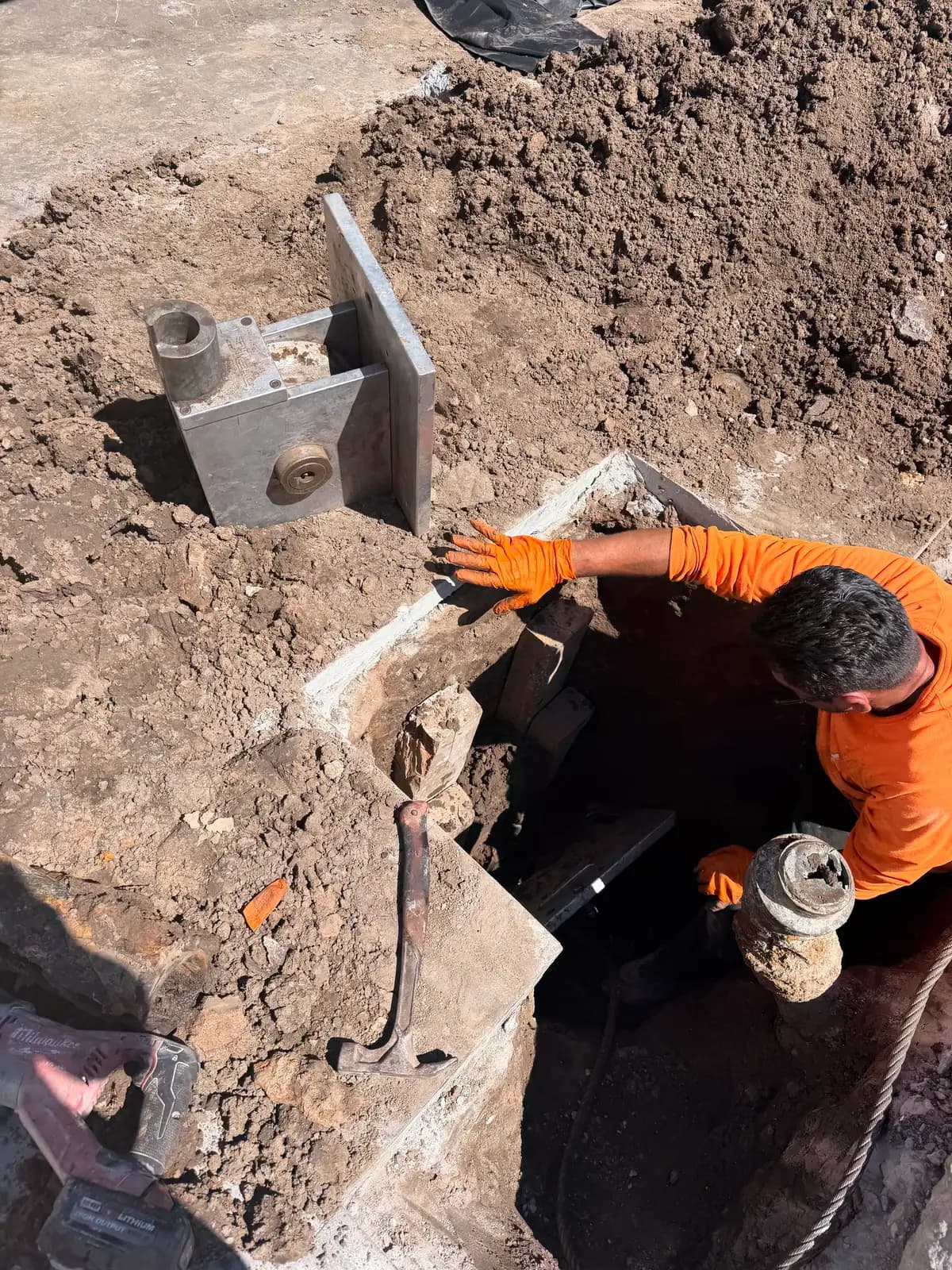 Technician working in a sewer cleanout access pit during a trenchless job