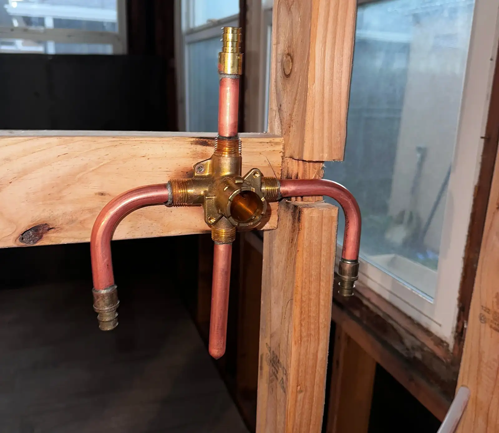 New tub and shower valve rough-in during a Lomita bathroom remodel, a brass valve body on wood blocking with copper stubs and PEX supplies