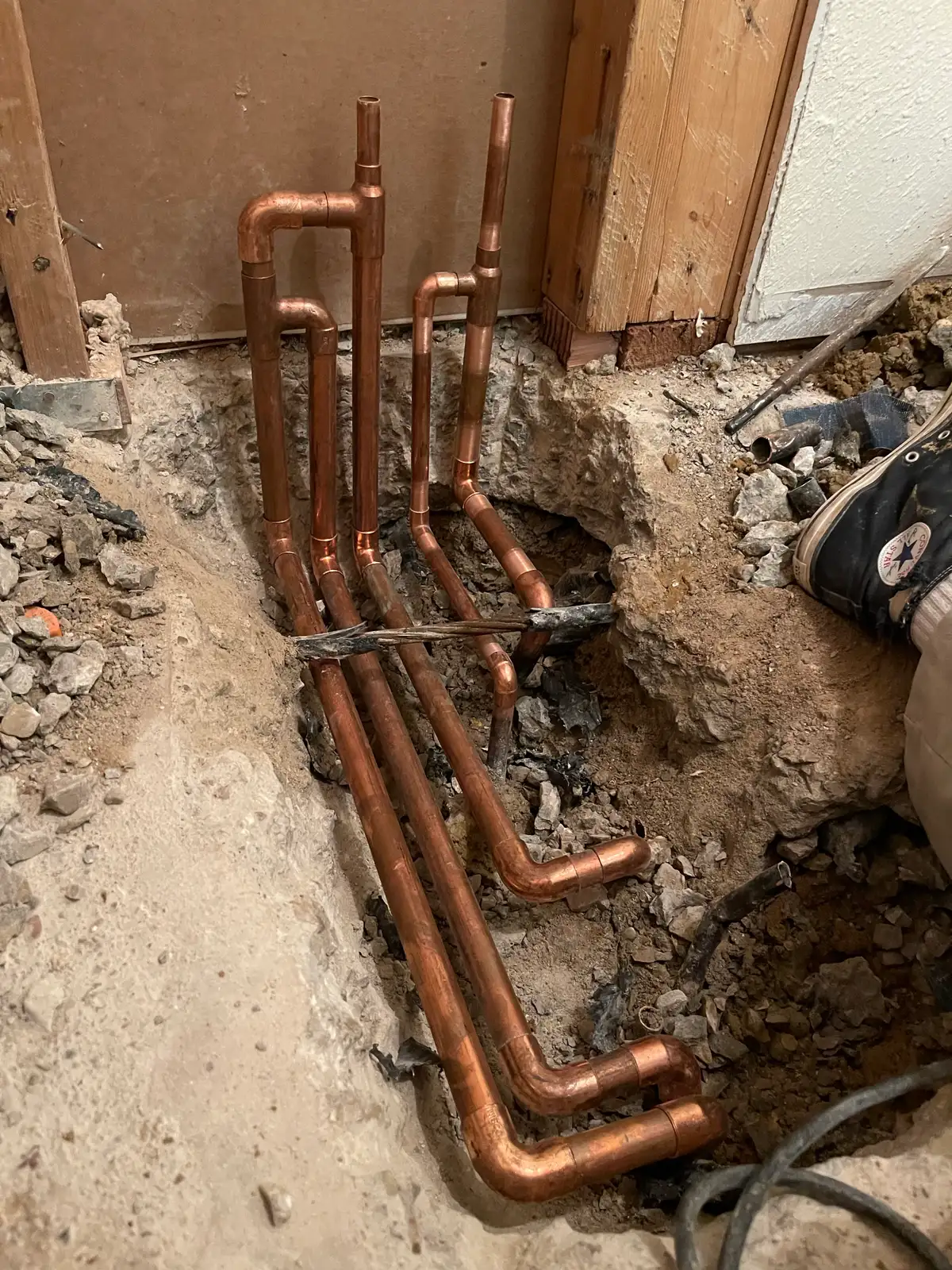 Water supply manifold serving lines routed through a concrete slab